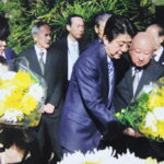 イビラプエラ公園内「開拓先没者慰霊碑」に献花する本橋さんと安倍元首相（右から、提供写真）