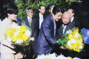 イビラプエラ公園内「開拓先没者慰霊碑」に献花する本橋さんと安倍元首相(右から、提供写真)