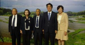後小畑のパネルの前で記念撮影する（左から）西村顧問、伊藤事務局長、要田会長、安倍総理、昭恵夫人（２０１４年）