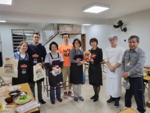 川村次長（右から３人目）に「赤べこ」を手渡す今井会長（同４人目、提供写真）