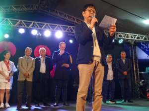 開会式の様子。あいさつする在サンパウロ総領事館の山内隆弘領事部長。後列左2人目からソロカバ文協(UCENS)のセルジオ・モリ会長、ソロカバ市副市長、ホドリゴ・マガニャット同市長