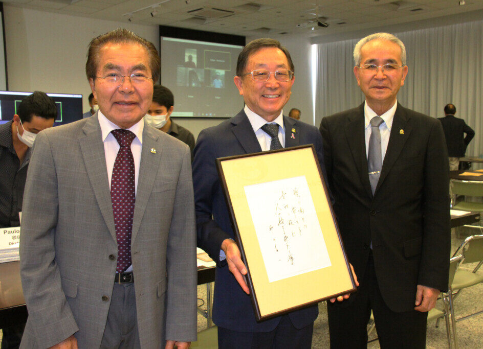 故・神内氏の直筆額と写る菊地評議員会会長、税田会長、与儀評議員会第１副会長（右から）