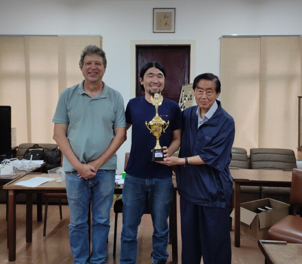 優勝トロフィーを持つ浜公志郎さん（中央）とジェームス会長（左）、川合昭顧問（右）