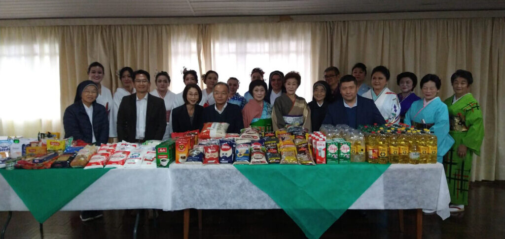 寄贈された基礎食料品を前にした龍千多会関係者（提供写真）