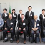 後列左から森岡、松田、公平、林、谷口さん。前列に派遣先関係者と中央に江口所長