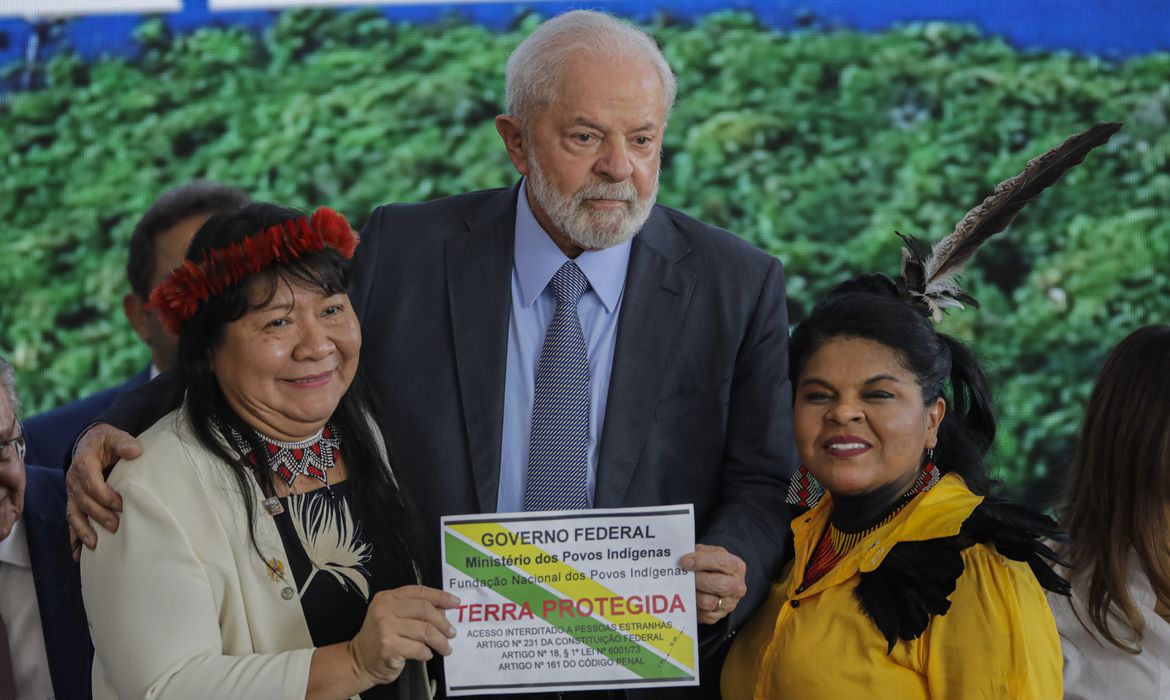 先住民保護区制定の書類を掲げるジョエニア・ワピシャナ国立先住民族保護財団総裁とルーラ大統領、グアジャジャラ先住民族相（左から）（©Joedson Alves/Agencia Brasil）