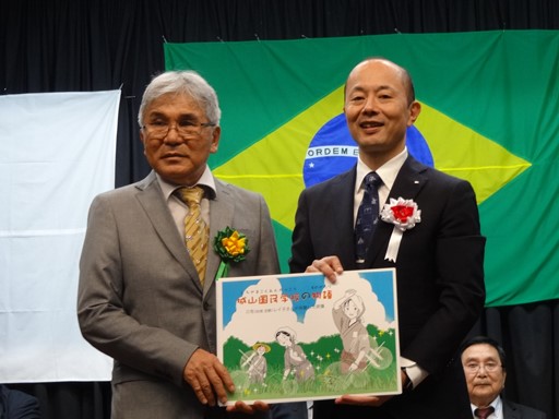 森繁親長崎県人会会長に紙芝居を贈呈する鈴木史朗長崎市長（右）