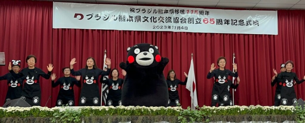 熊本県人会６５周年式典で熊本リズムメロディーのメンバーと「くまモンダンス」を披露するくまモン
