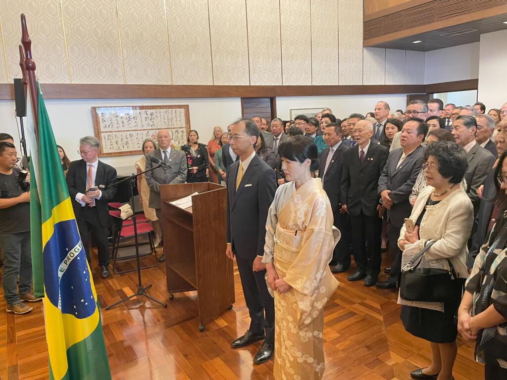 サンパウロ市の総領事公邸で行われた祝賀レセプションで国歌斉唱を行う様子。中央に清水総領事夫妻