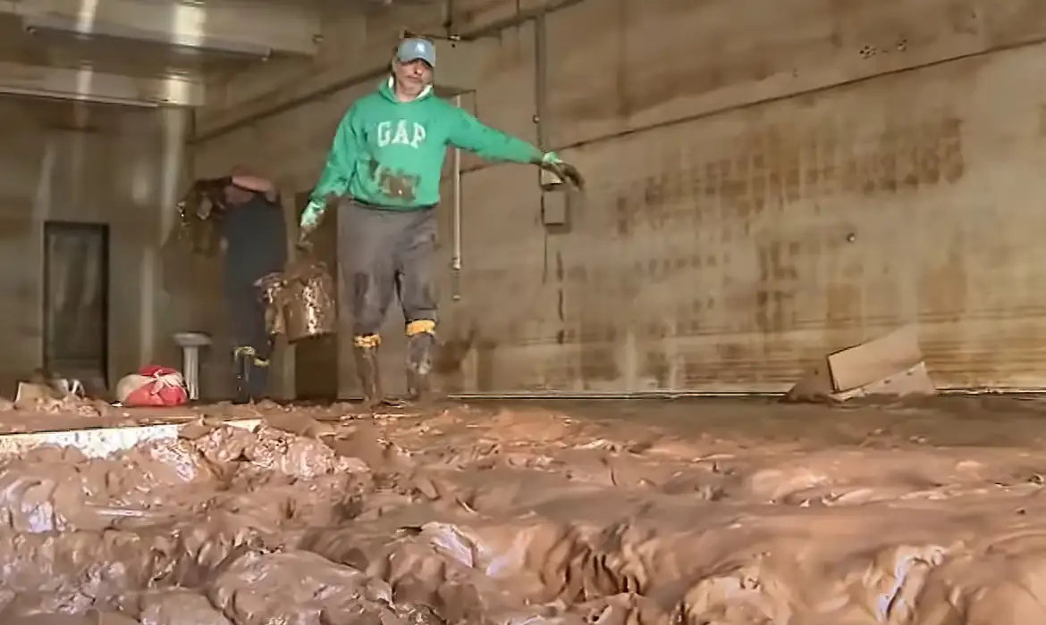 施設の中に溜まった汚泥の除去作業を行う男性（ラジャアド市、©Frame/TV Brasil）