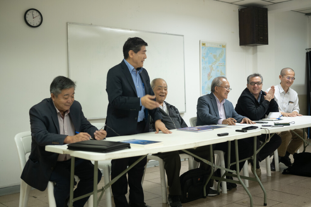 左から上原ミルトン定雄沖縄県人会前会長、説明会の主旨を説明する高良会長、宮城代表、島袋栄喜元会長、奥原マリオさんら