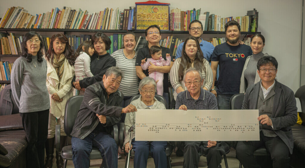 家系図を持ちながら集まった笑顔の今野一族と山口さん（右下）