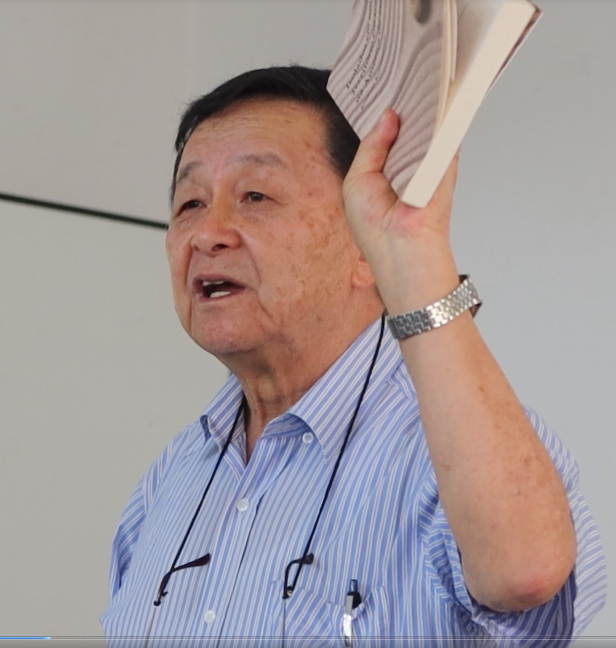 『Isolados em um Território em Guerra na América do Sul』を手に、当時の両親の気持ちを思いながら講演する宮村さん