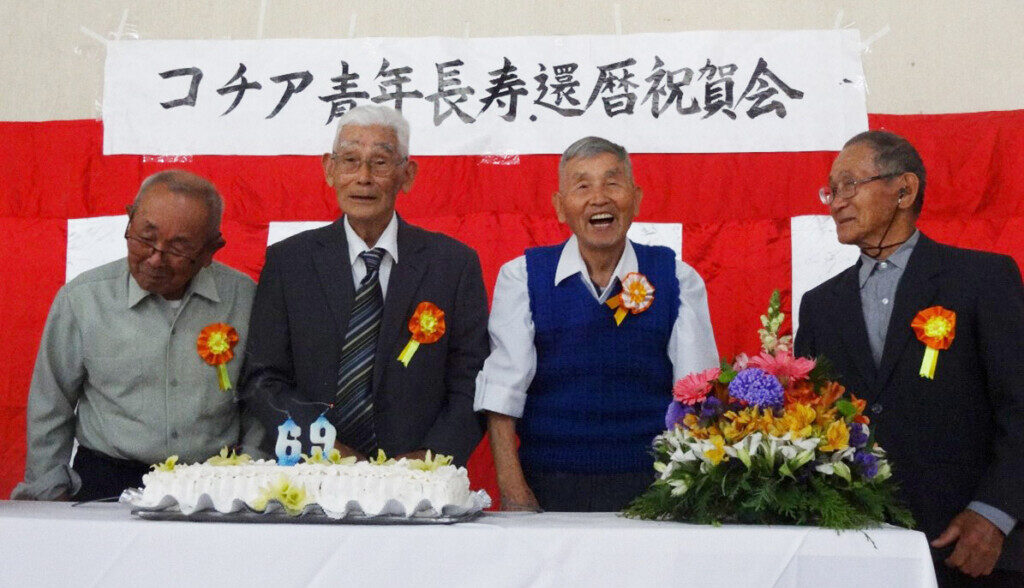 コチア青年連絡協議会創立69周年を祝うケーキの前に立つ長寿者たち