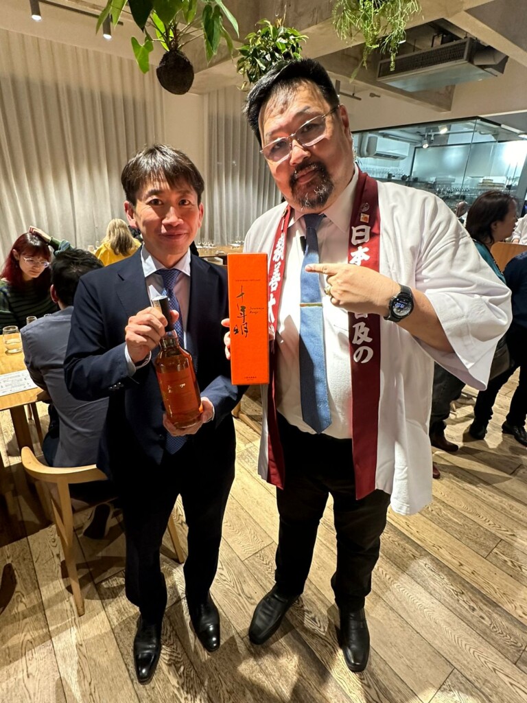 ジャパニーズウィスキー「十年明」を手にする三浦社長（左）と酒専門家の飯田アレシャンドレ龍也さん