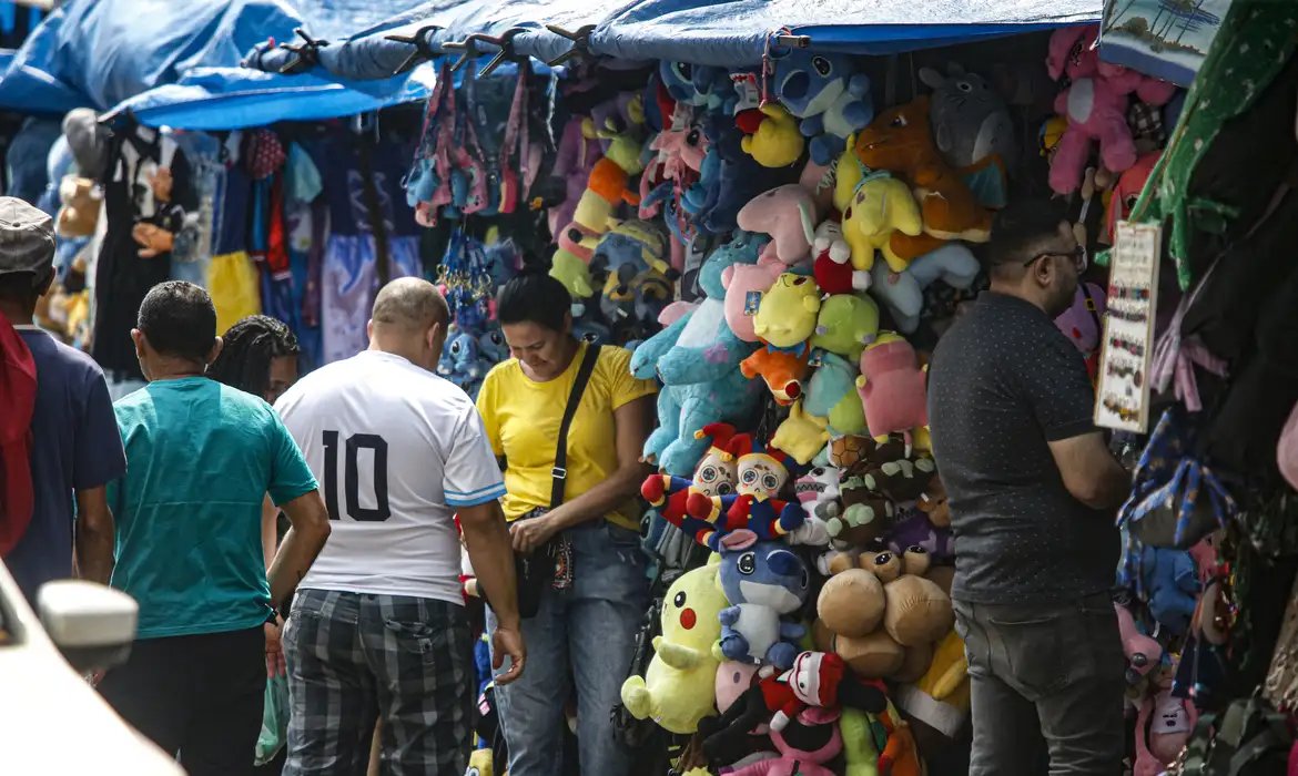 日焼け避けのビニールシートを張った店頭で買い物をする人々（© Paulo Pinto/Agência Brasil）