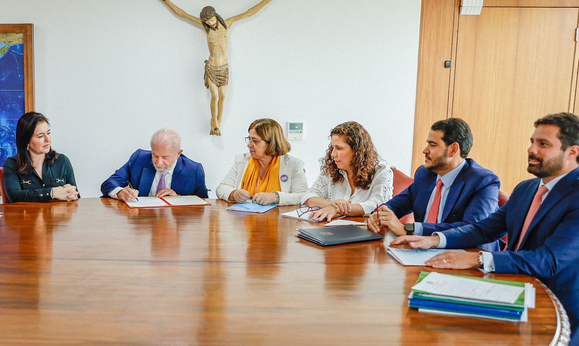 シモーネ・テベテ企画相、シダ・ゴンサルヴェス女性相、エステル・ドウェック管理革新相が同席する中、新法に署名するルーラ大統領（Foto: Ricardo Stuckert/PR）