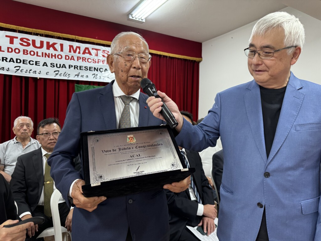 ACAL50周年の記念プレートを池崎カルロスさん（右）と喜ぶ矢野会長