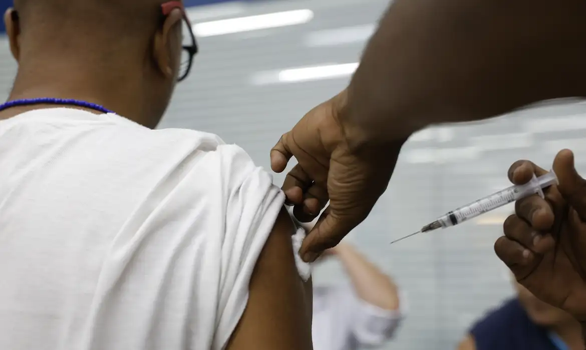 予防接種を受けている男性（© Fernando Frazão/Agência Brasil）