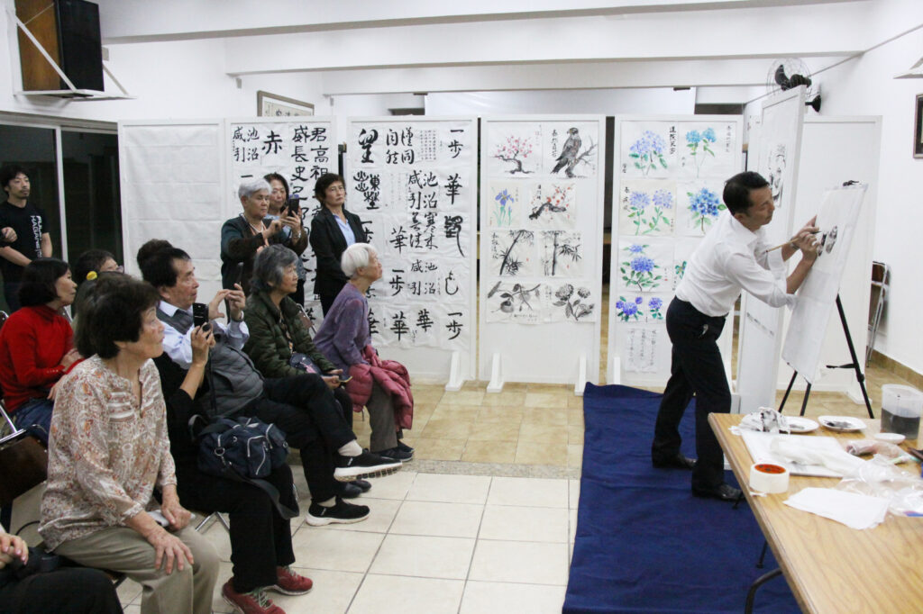 墨絵のデモンストレーションを行う林大使（右側）