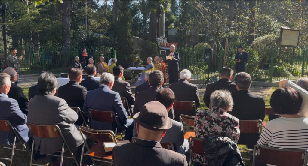 慰霊碑前で挨拶する谷口会長